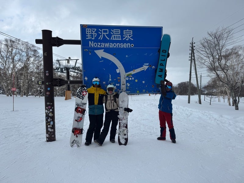Our crew with snowboards at the Nozawa Onsen sign